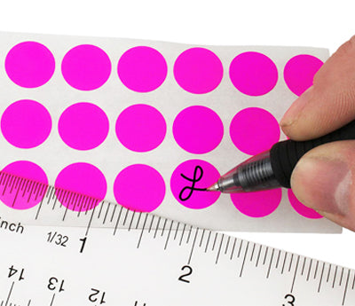 A Person's hand writing the letter L on a sticker with a felt tip marker