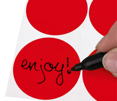 A Person's hand writing the word Enjoy on a Removable sticker with a felt tip marker
