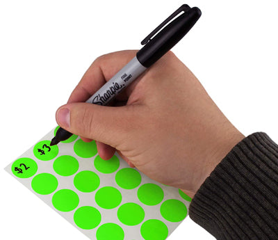 A Person's hand writing pricing on a sticker with a felt tip marker