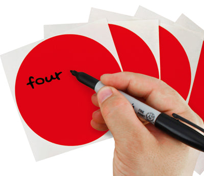 A Person's hand writing the word four on a sticker with a felt tip marker