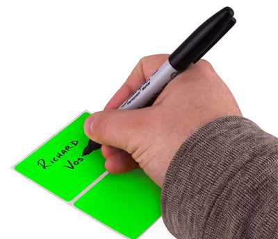 A Person's hand writing a name on a sticker with a felt tip marker