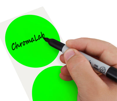 A Person's hand writing the word ChromaLabel on a sticker with a felt tip marker