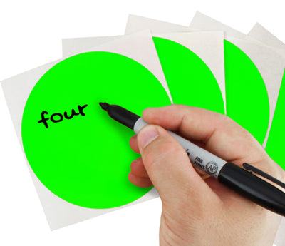 A Person's hand writing the word four on a sticker with a felt tip marker