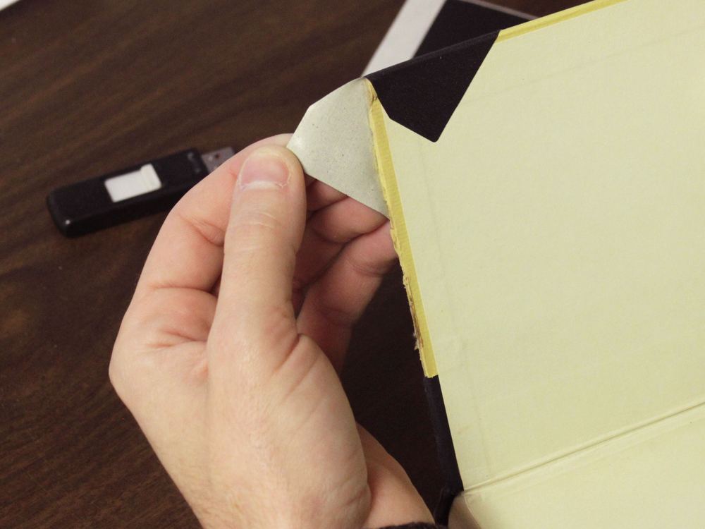 A black cloth corner being folded over a book's corner