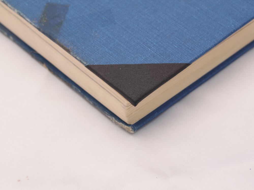 A black cloth corner on a blue cloth hardback
