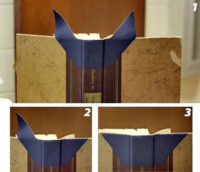 A navy cloth wing folded over the top of a book's spine, in three steps