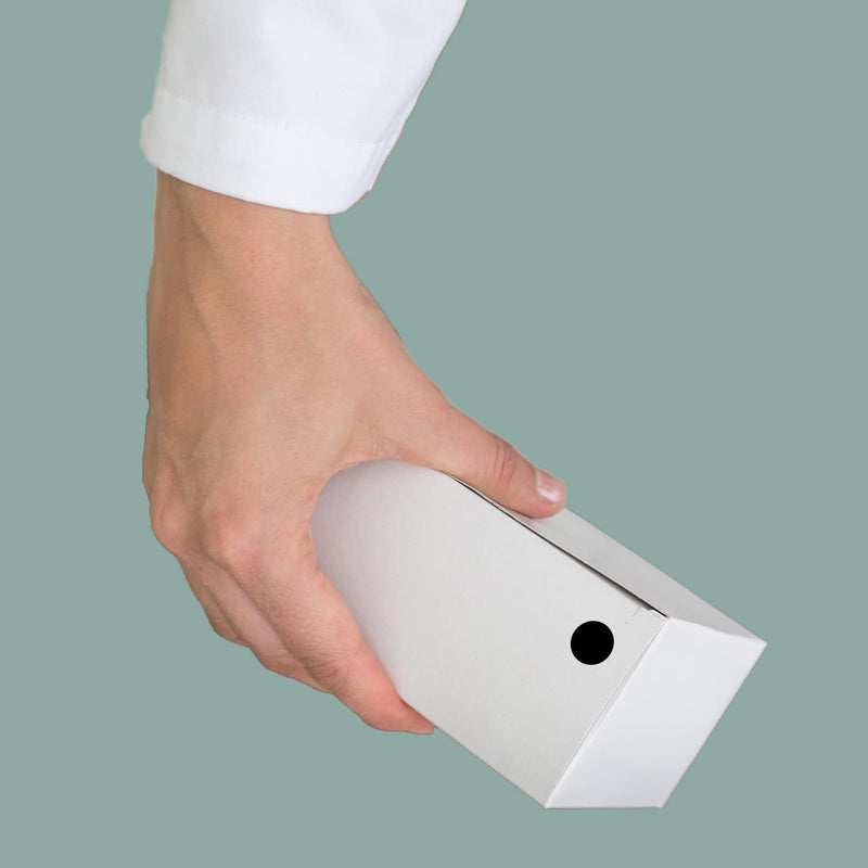 A hand holding a white carton marked with a 1/2 inch black dot